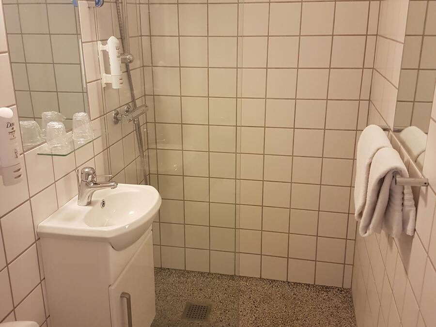 A small bathroom with a sink, mirror, and shower.
