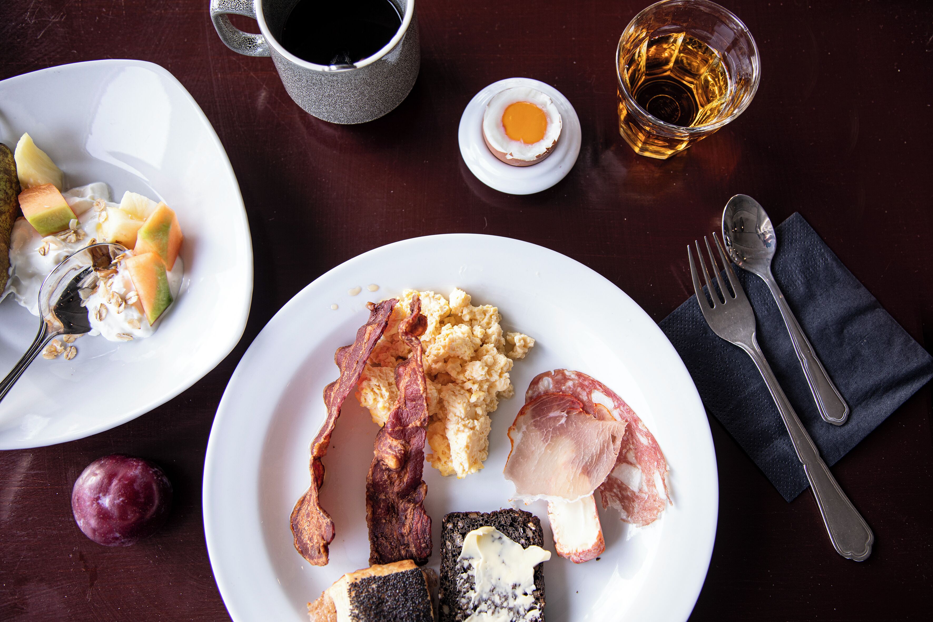 Un desayuno con platos de comida, una taza de café y un vaso de whisky.