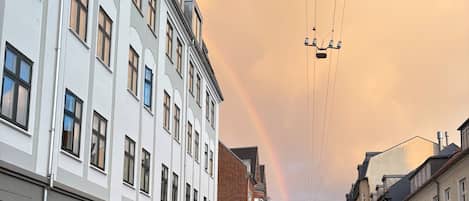 Una calle con edificios, un camión y un arcoíris.