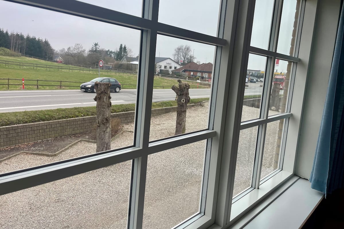 A view through a window with a wooden post and a road with a speed limit sign.