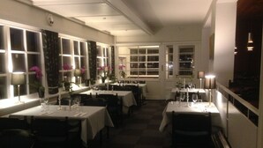 A restaurant with multiple tables and chairs, white walls, and large windows. - Blommenslyst Kro (Blommenslyst)