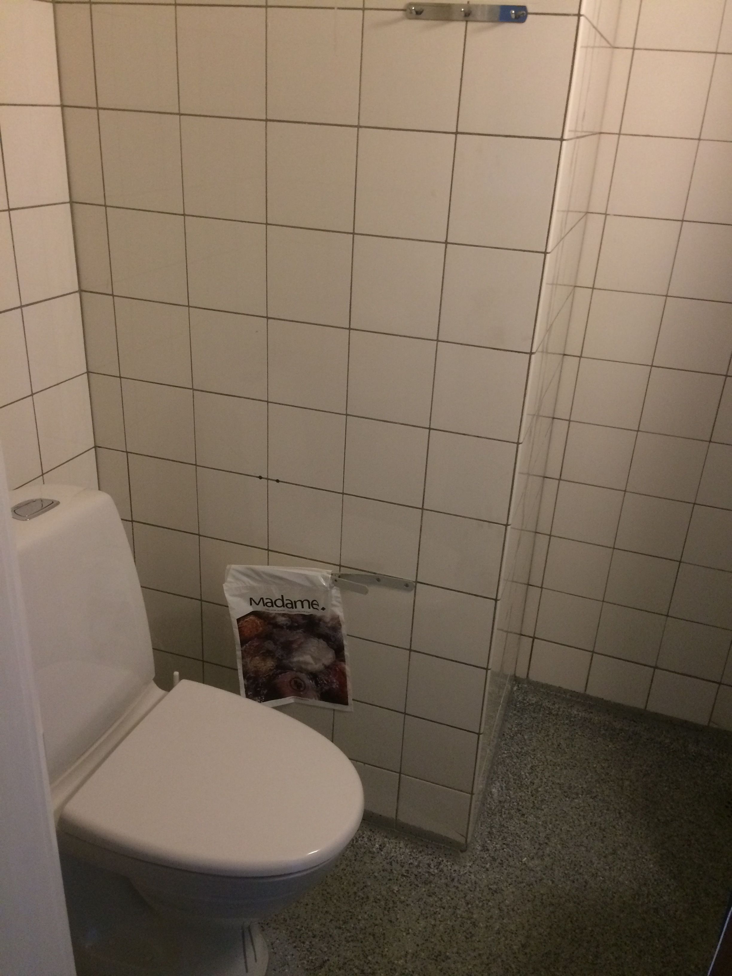 Un bagno con un water, uno spazio doccia e un rivestimento in piastrelle.