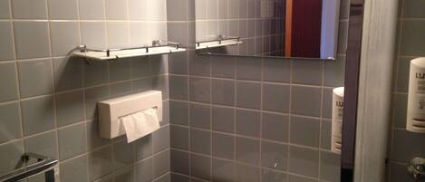 A bathroom with grey tiles, a white sink, and a mirror.