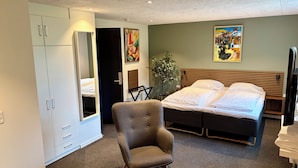 A hotel room with a bed, a chair, a wardrobe, and a painting on the wall. - Blommenslyst Kro (Blommenslyst)