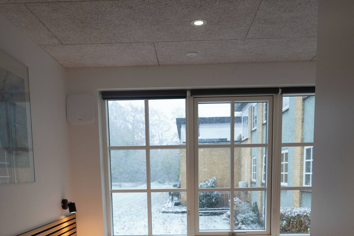 A bedroom with a single bed, a window with a view of a snowy landscape, and a radiator.