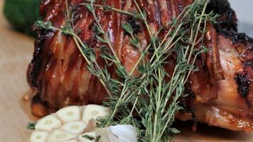 Ein gebratenes Schweinelachsfilet, garniert mit Kräutern und Knoblauch, auf einem Holzbrett.