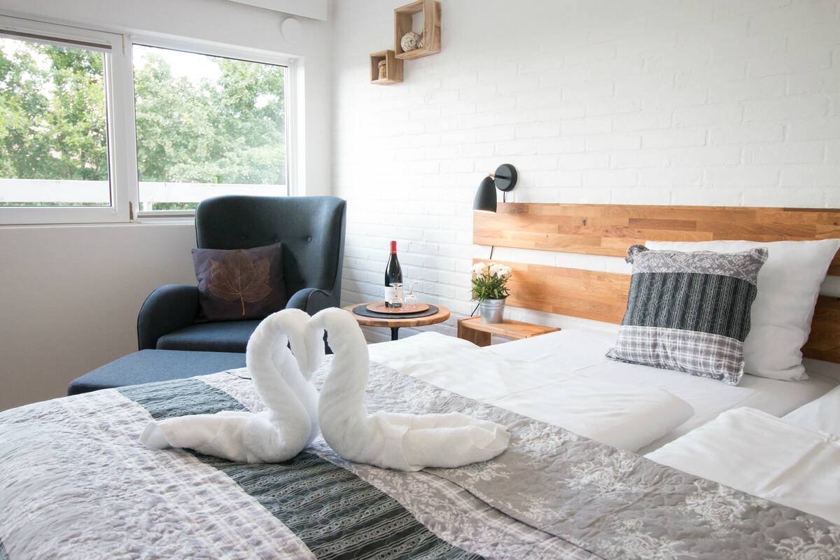 Une chambre d’hôtel avec un lit, une chaise, une table de chevet et une fenêtre.