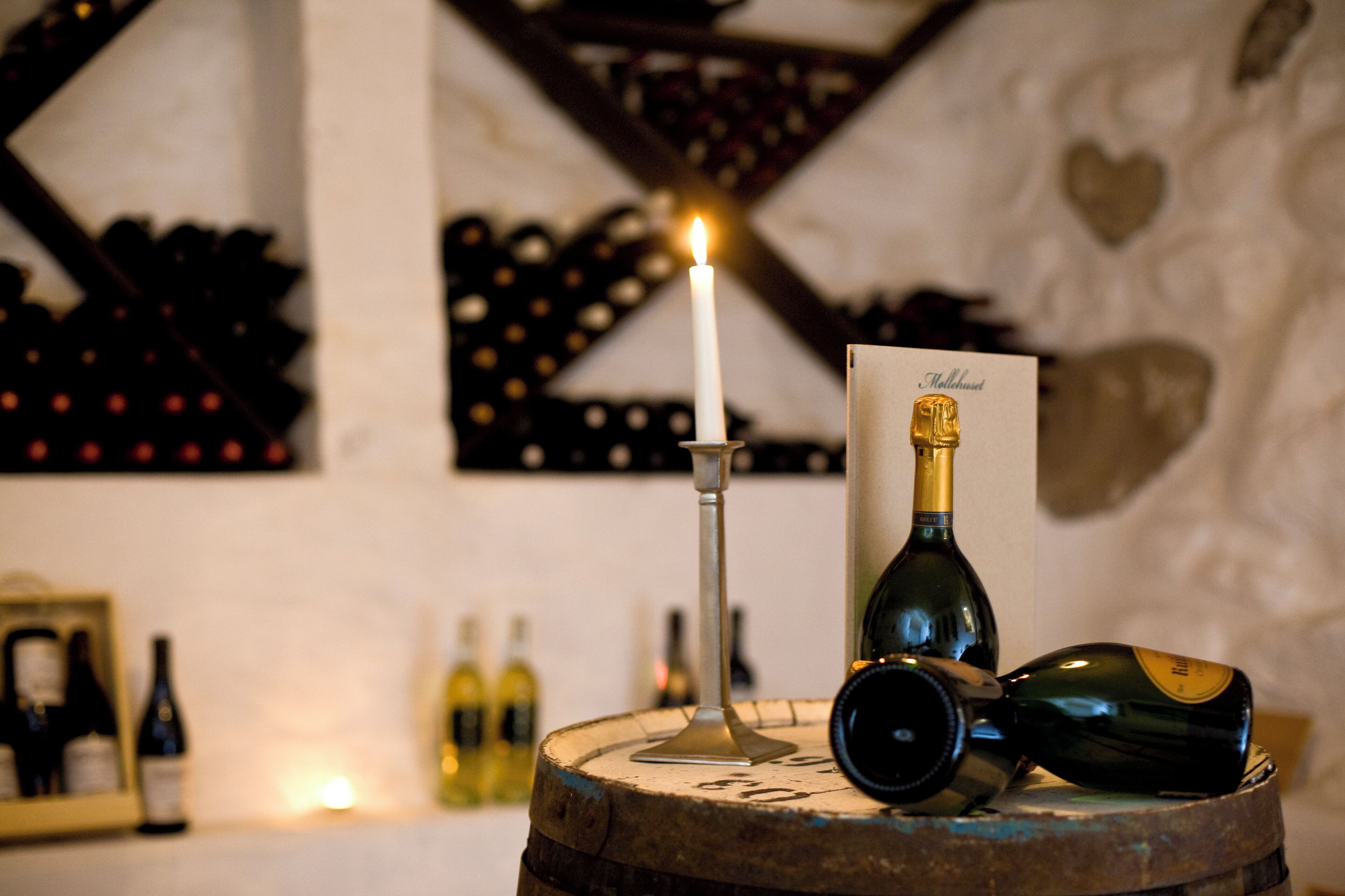 Un tonneau à vin sur lequel sont posés une bougie, une bouteille et un verre.