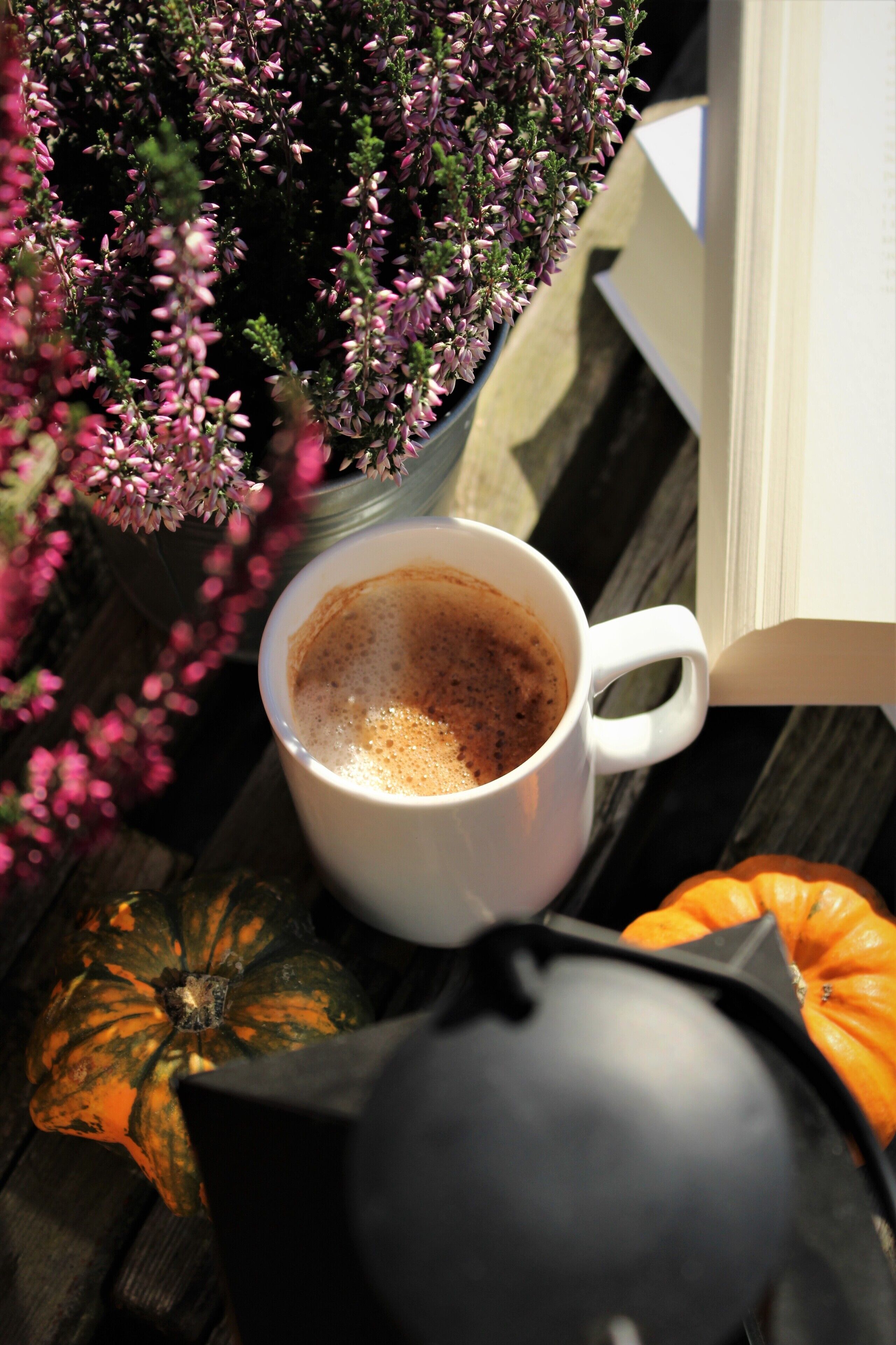 Una tazza da caffè bianca su un piano di legno, con un libro e elementi decorativi.