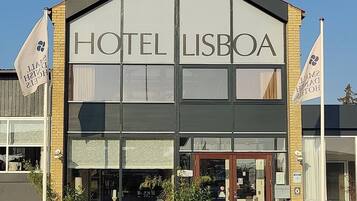 Een hotel genaamd "HOTEL LISBOA" met een moderne gevel, grote ramen en een duidelijke ingang.