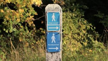 A wooden signpost with directional arrows and symbols indicating paths to 'Hærvejen' and 'Nordøststien'.
