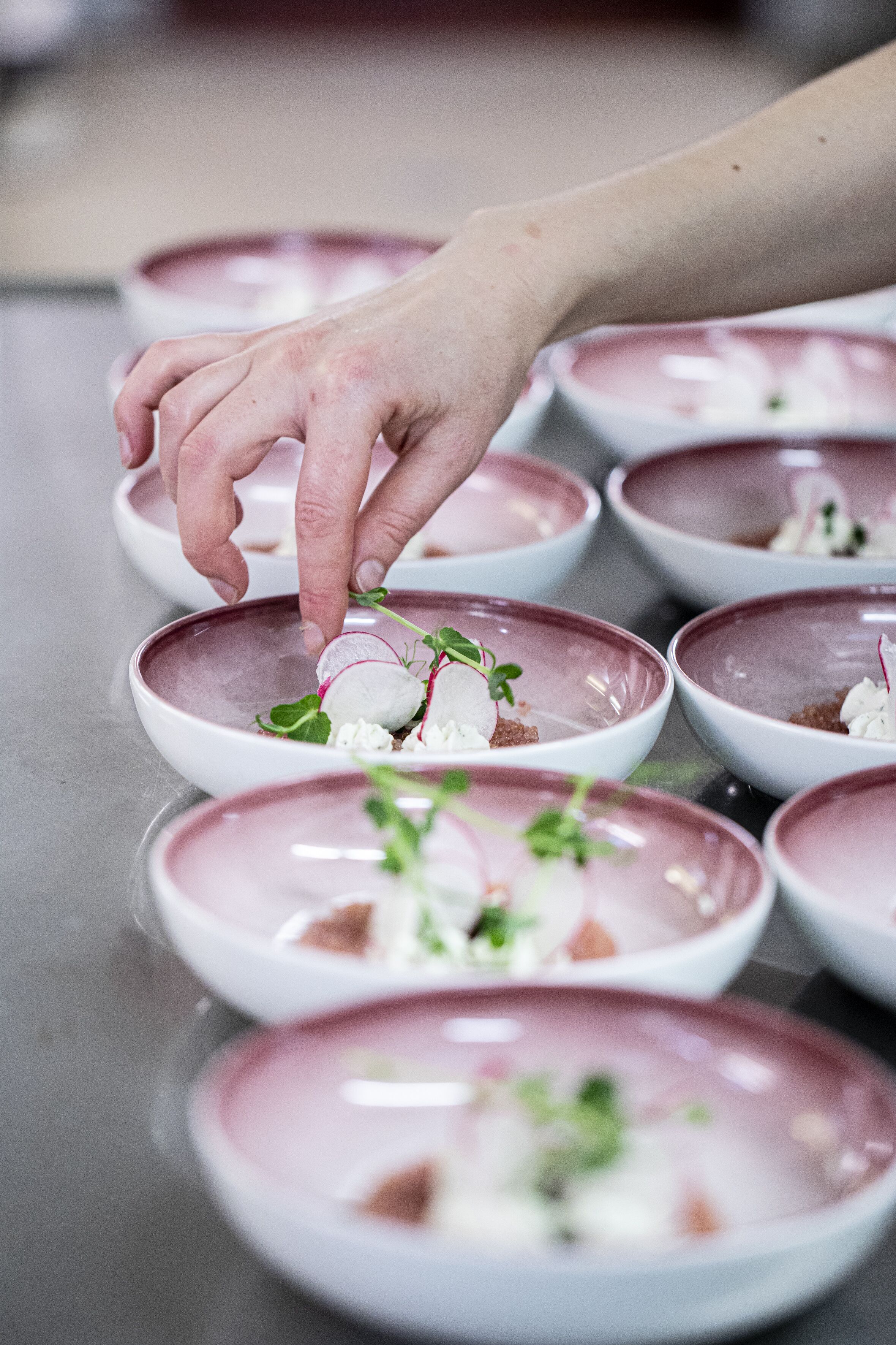 A hand placing a garnish on a dish.