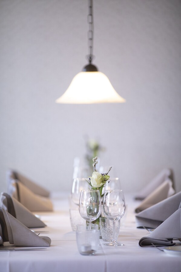 Une table dressée pour le repas, avec un luminaire suspendu au-dessus.