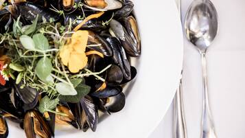 A plate of mussels with greens and herbs.