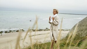 Eine Person steht am Strand mit Blick auf den Ozean.