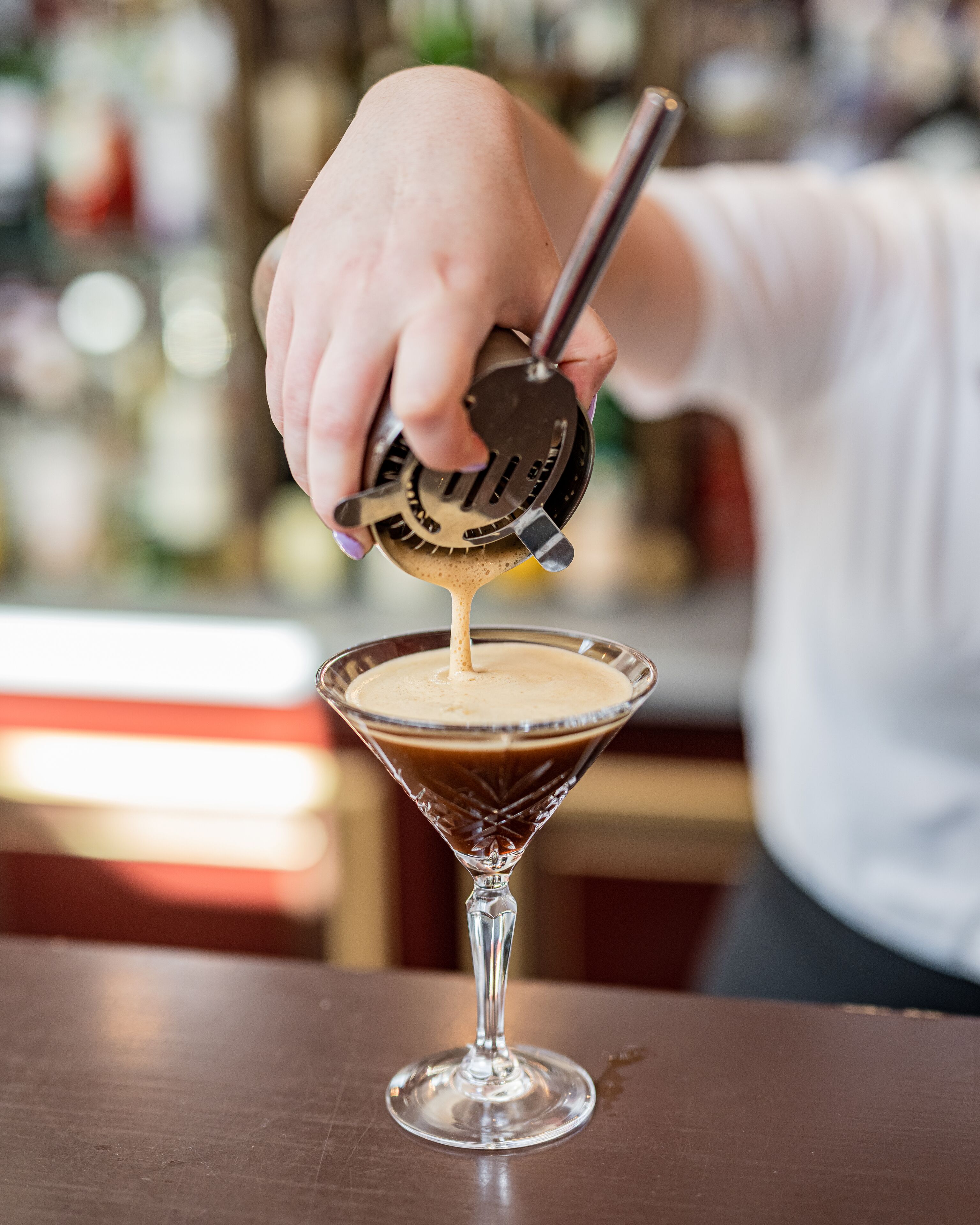 Una persona sirviendo una bebida en una copa de martini.
