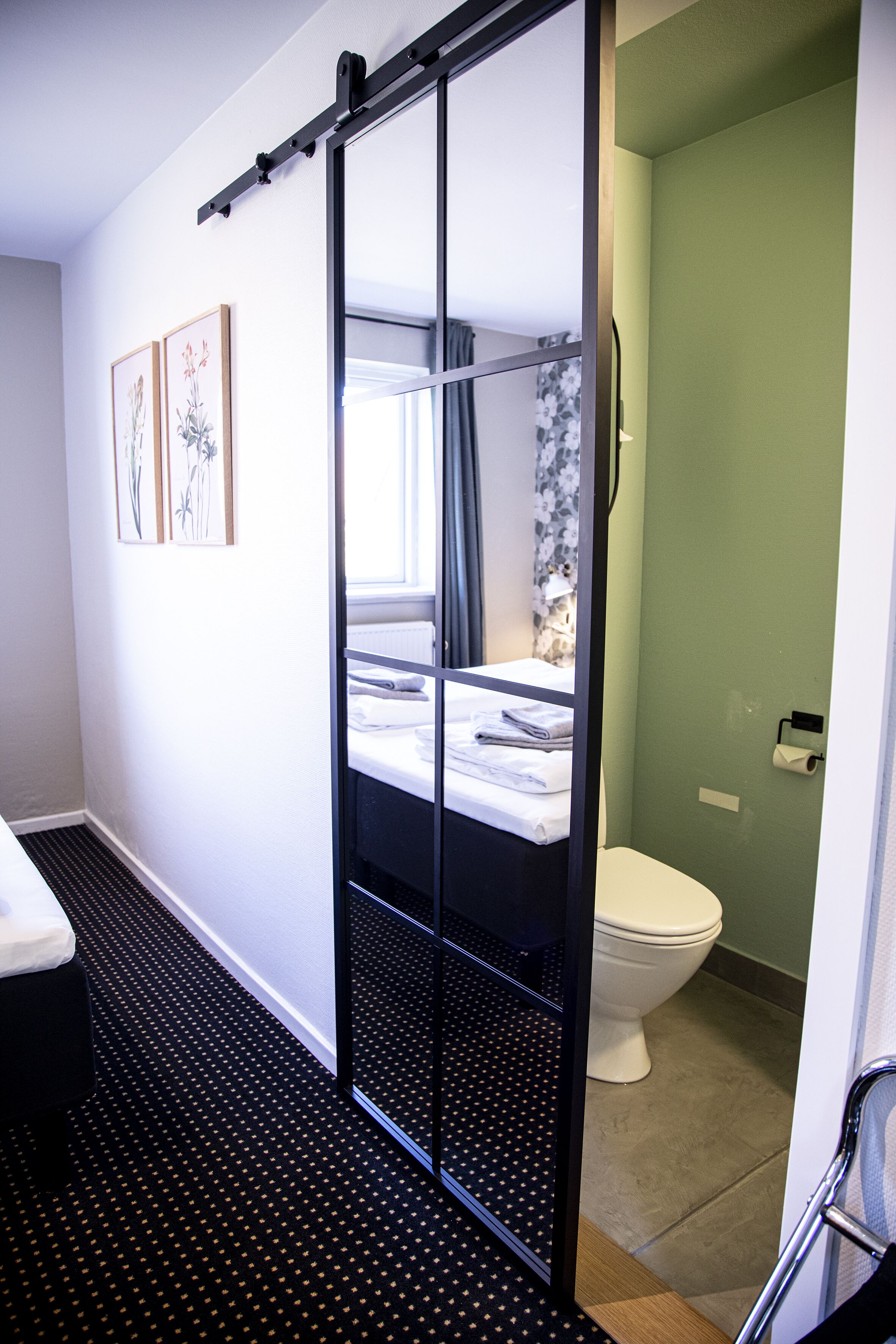 A compact hotel room with a bunk bed, a toilet, and a shower area.