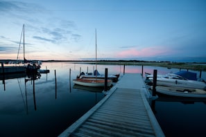 Una marina tranquila con barcos amarrados a muelles de madera, rodeada de aguas serenas y un cielo despejado.