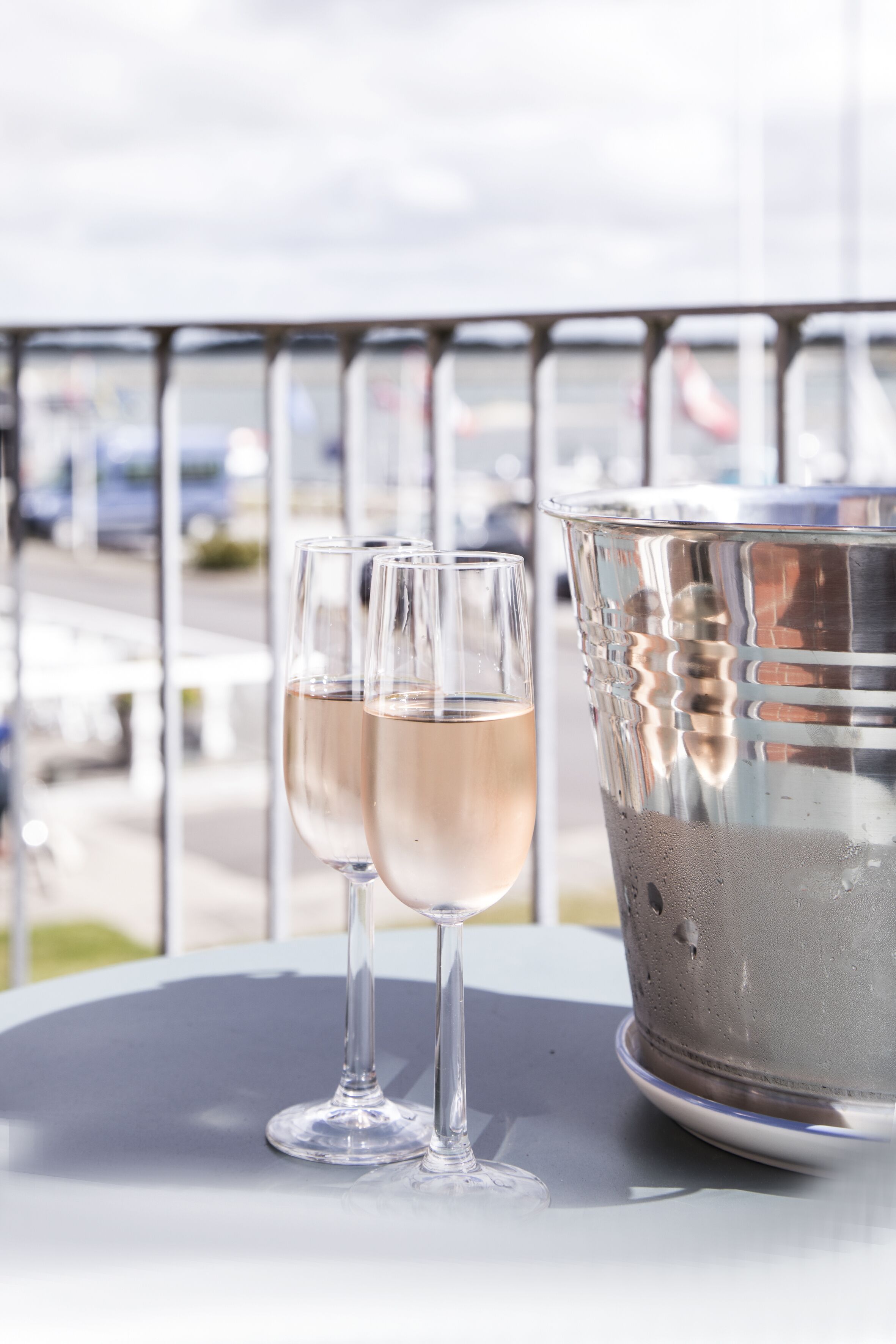 Two glasses of champagne on a table with a metal bucket beside them.