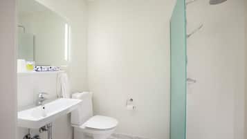 Un baño moderno con lavamanos blanco, inodoro y cabina de ducha de vidrio.