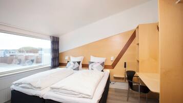 Et moderne hotelværelse med en seng, et skrivebord og en stol.