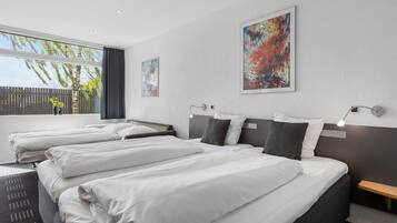 Habitación de hotel con dos camas, un ventanal grande y obras de arte en las paredes.