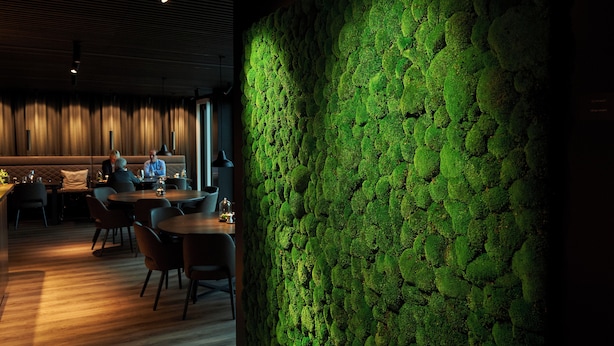 A restaurant with a green moss wall, wooden flooring, and modern furniture. - Hotel Hedegaarden (Vejle)