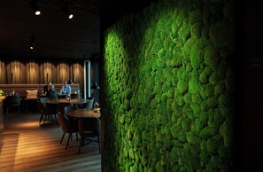 A restaurant with a green moss wall, wooden flooring, and modern furniture. - Hotel Hedegaarden (Vejle)
