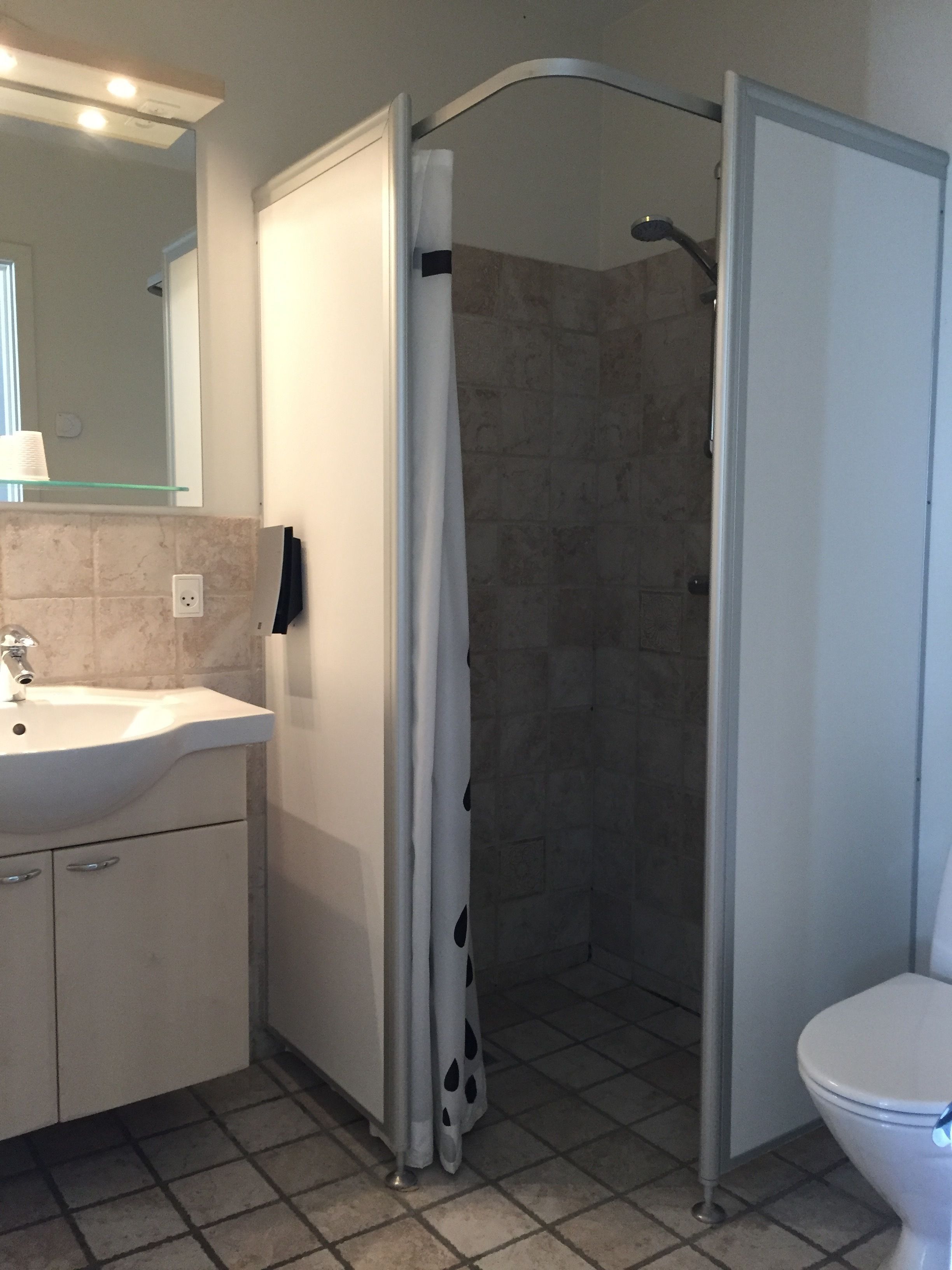 A bathroom with a sink, mirror, shower, and toilet.