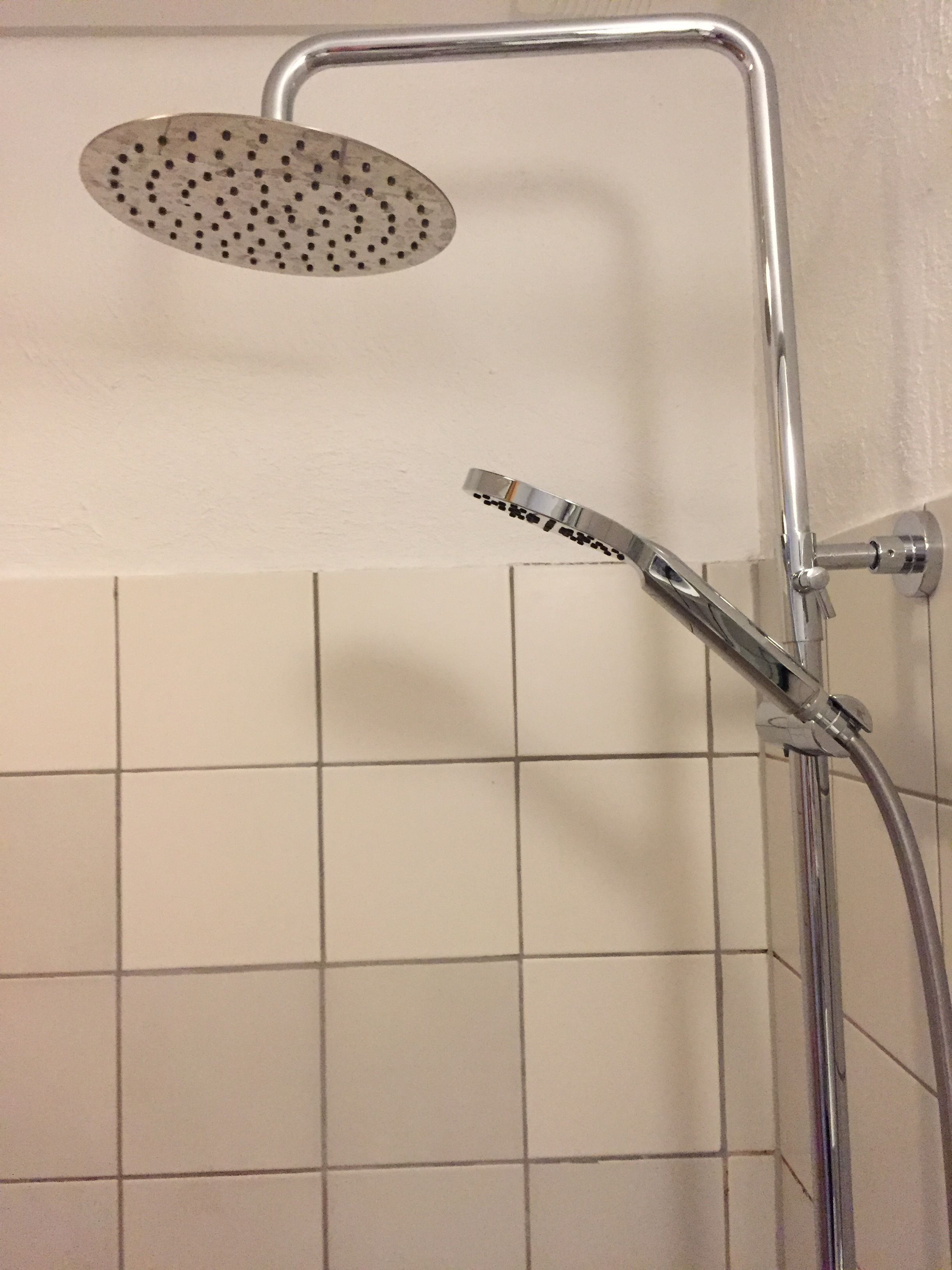 A shower with a handheld showerhead and a wall-mounted rain showerhead.