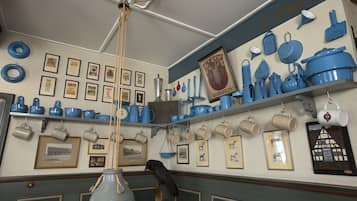 Una cocina con utensilios de cocina azules y blancos, cuadros en las paredes y una lámpara colgante.