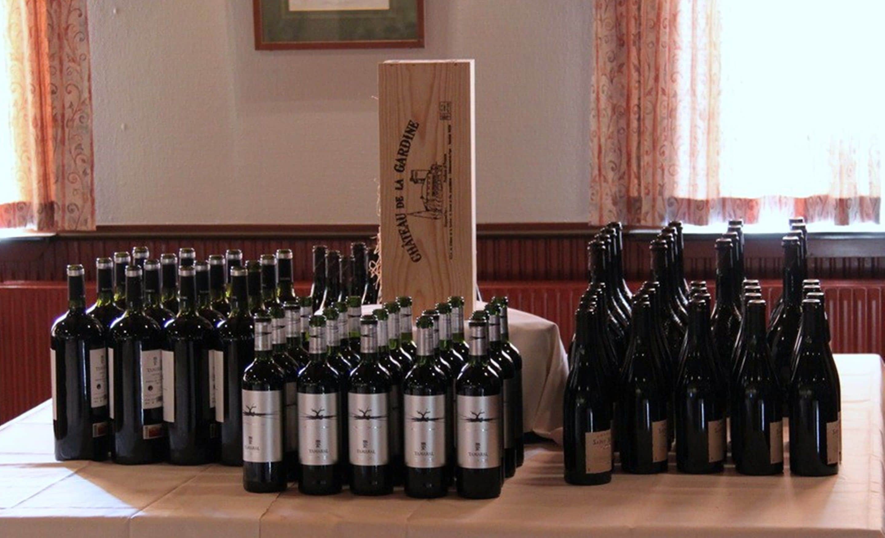 A table with multiple wine bottles arranged in rows.