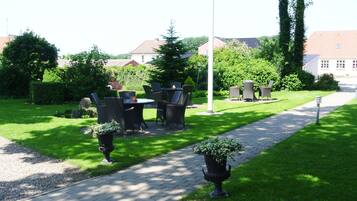 A garden with a paved walkway, outdoor furniture, and a variety of plants.