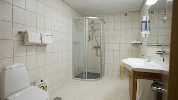 Casa de banho com sanita, cabine de duche e lavatório com espelho.