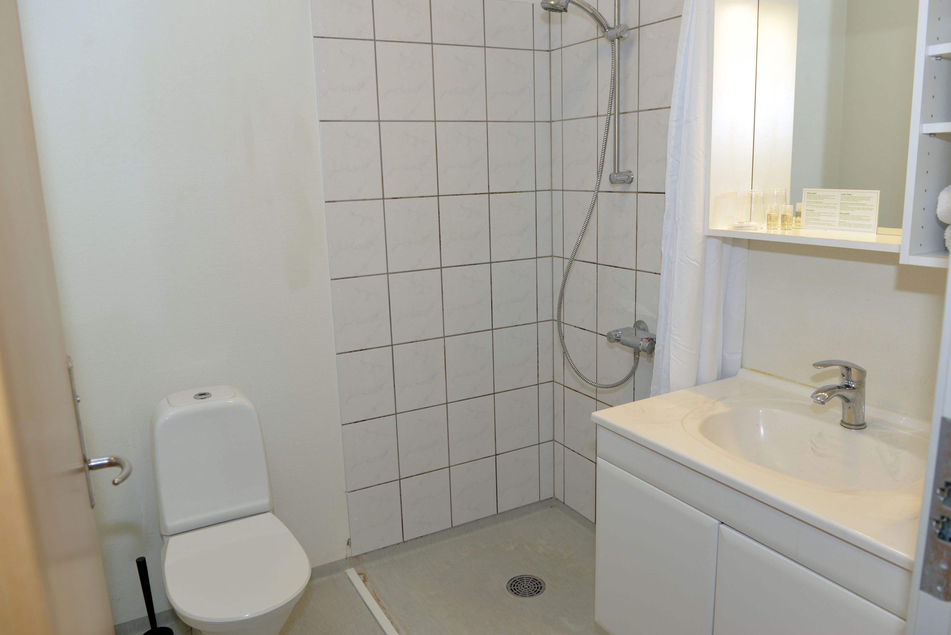 Ein kleines, sauberes Badezimmer mit Toilette, Dusche und Waschbecken.