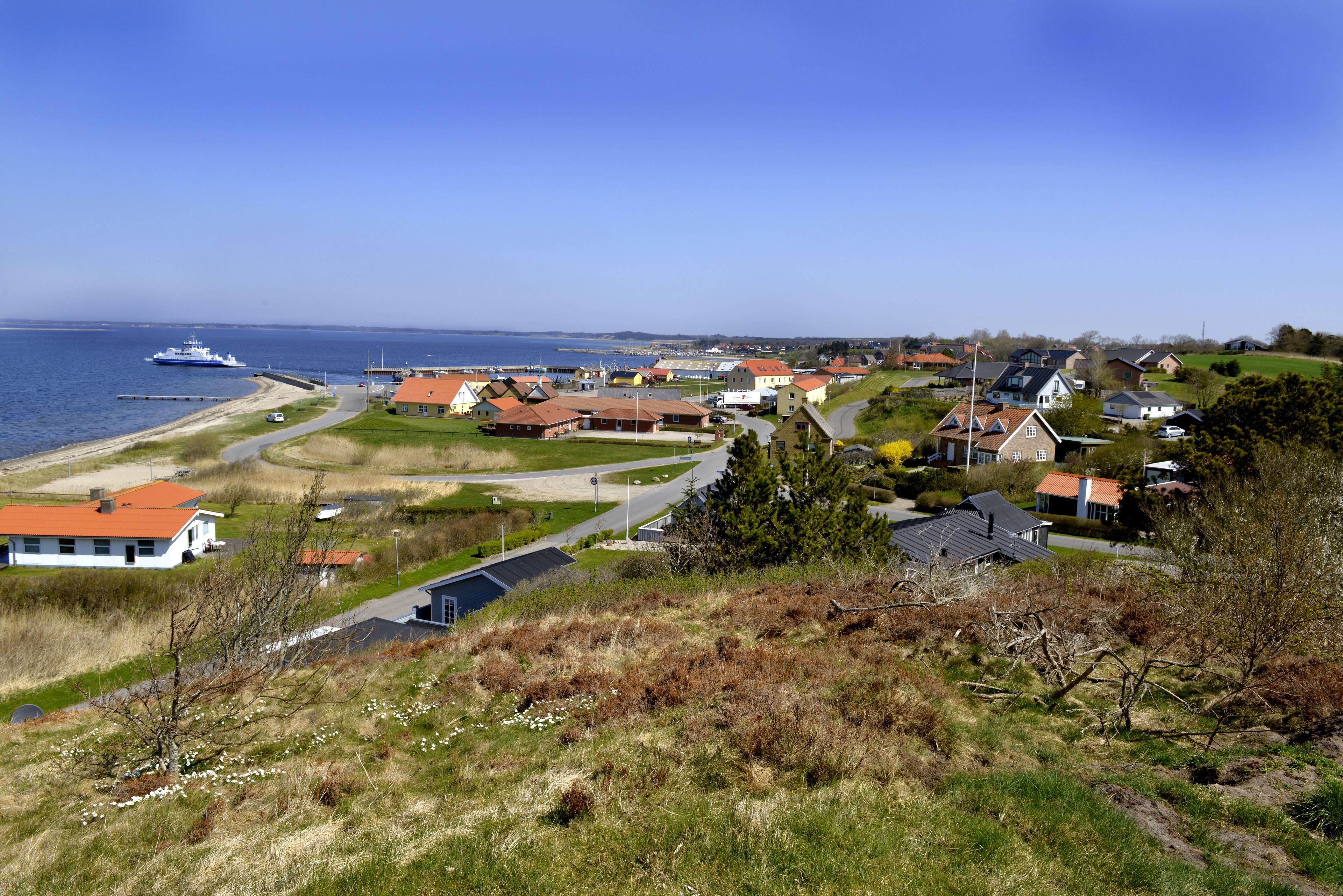 A coastal village with houses, a pier, and a boat.