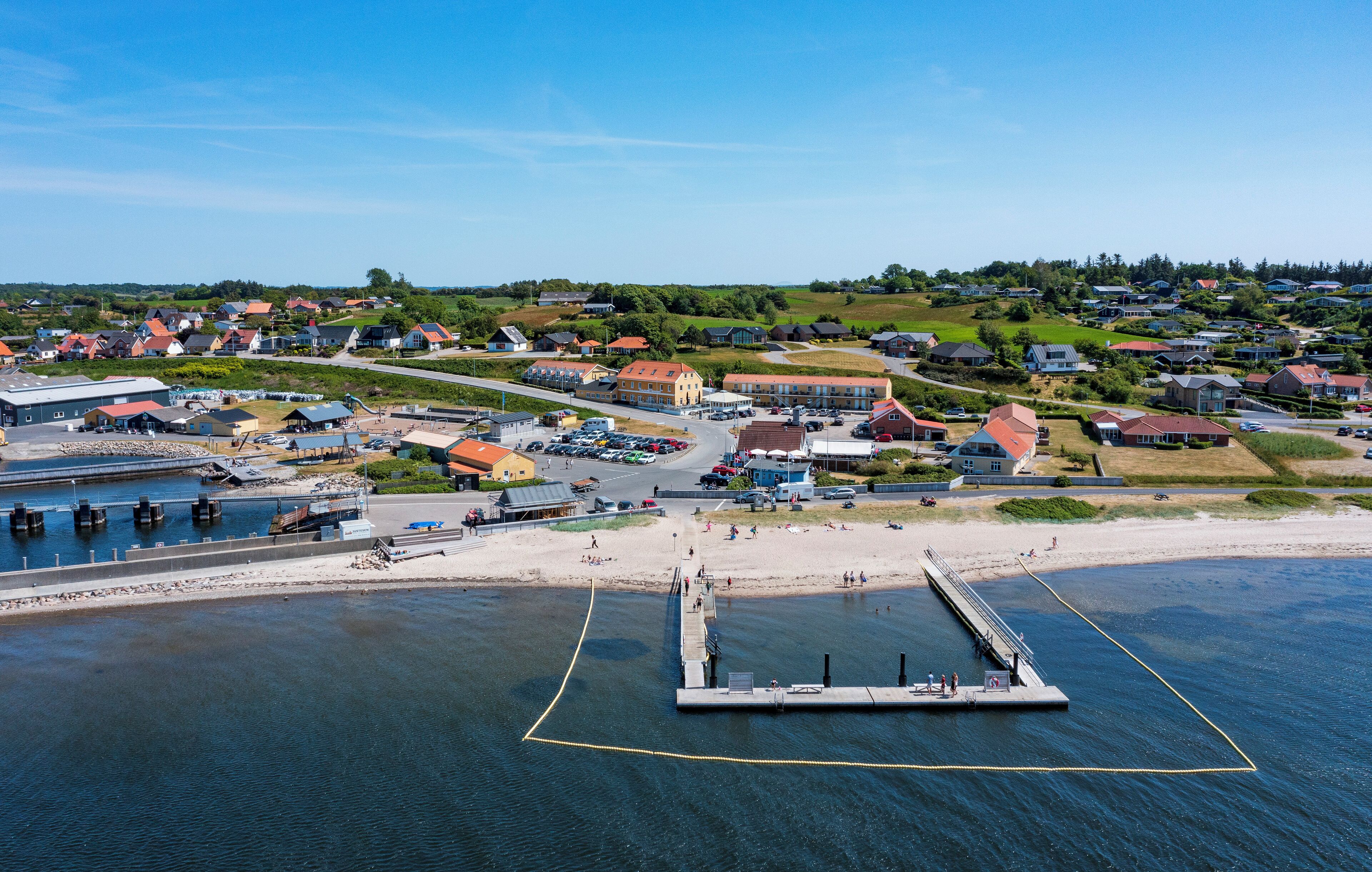 An aerial view of a coastal town with a pier, residential buildings, and a marina.