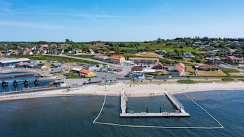 An aerial view of a coastal town with a pier, residential buildings, and a marina.