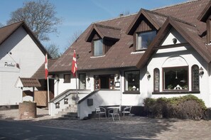 En traditionell byggnad med en vit fasad, en röd flagga och en trappa som leder upp till entrén.