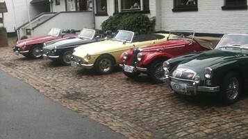 Una hilera de coches antiguos estacionados frente a un edificio con fachada blanca y techo oscuro.