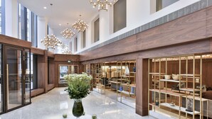 A spacious lobby with a marble floor, a central table with a vase of flowers, and a modern shelving unit displaying various items. - Royal Lancaster London (London)
