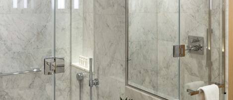 A modern bathroom with a glass shower enclosure, a marble sink, and a large mirror.