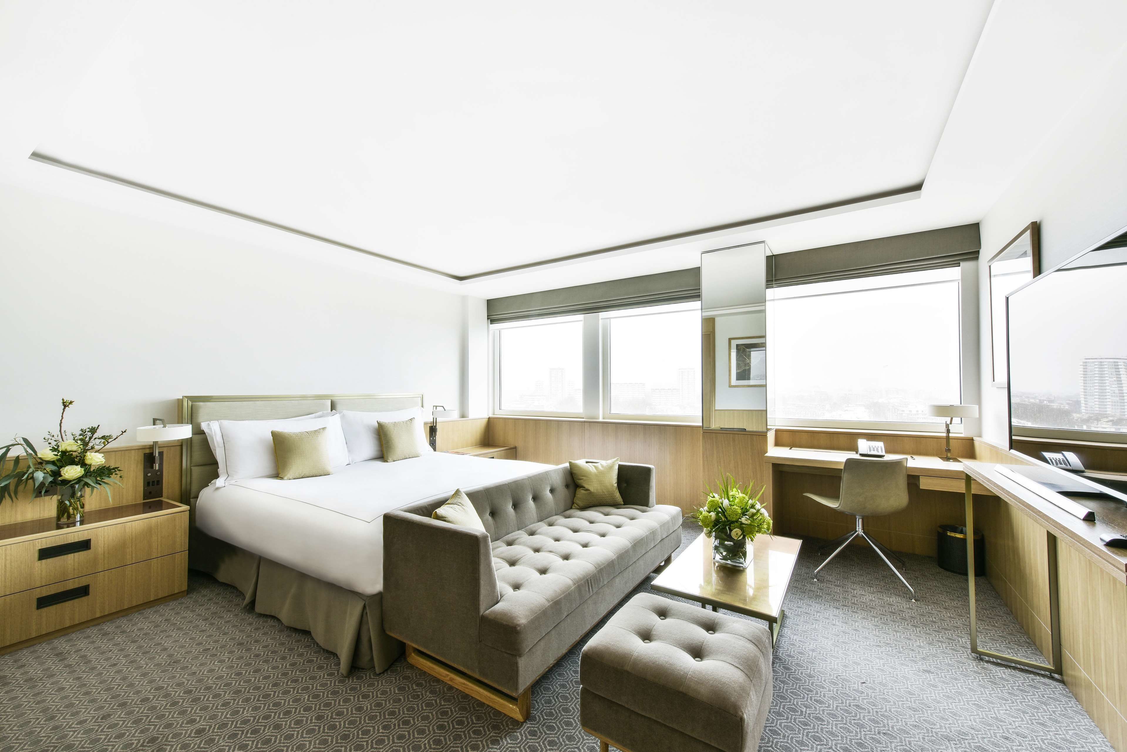 Una habitación de hotel moderna con cama, sofá, escritorio y un pequeño rincón de estar.