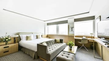 Una habitación de hotel moderna con cama, sofá, escritorio y un pequeño rincón de estar.