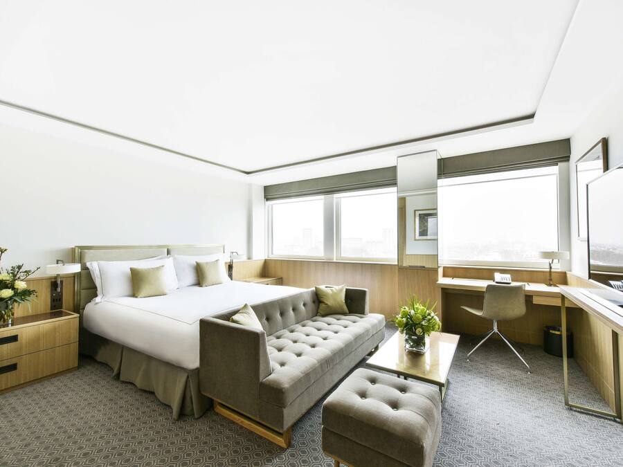 Una habitación de hotel moderna con cama, sofá, escritorio y un pequeño rincón de estar.