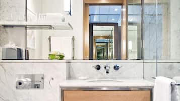 A modern bathroom with a marble countertop, a glass shower enclosure, and a wooden vanity.