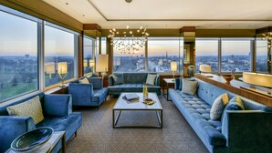 A spacious living room with a large city view, modern furniture, and a chandelier. - Royal Lancaster London (London)