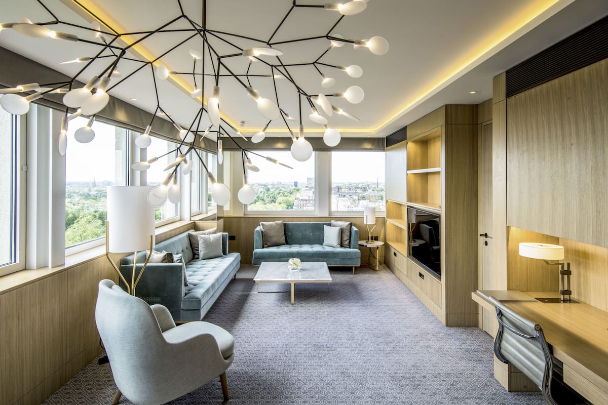 A modern living room with a sofa, armchair, coffee table, and a unique ceiling light fixture.
