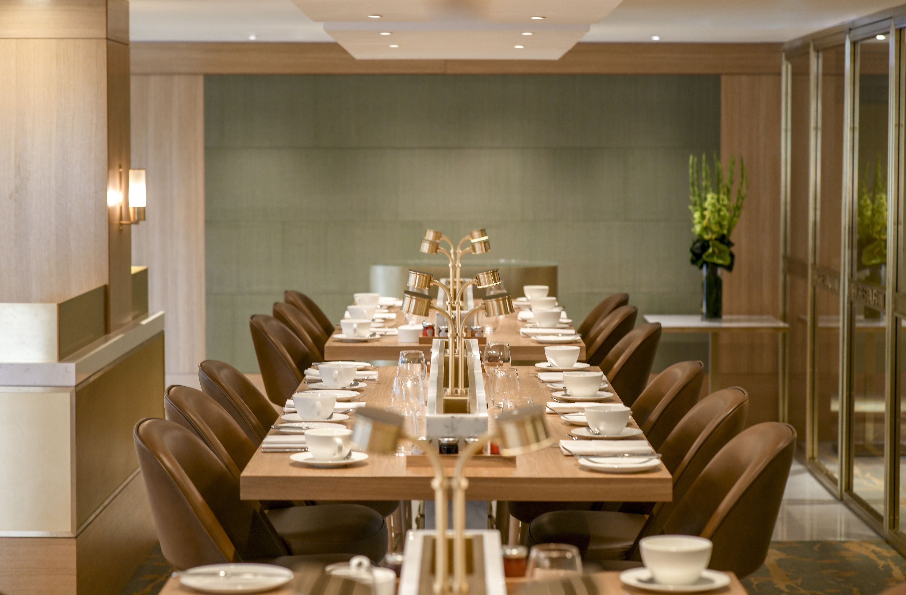 A dining area with a long table set for a meal, surrounded by chairs, with a modern interior design.