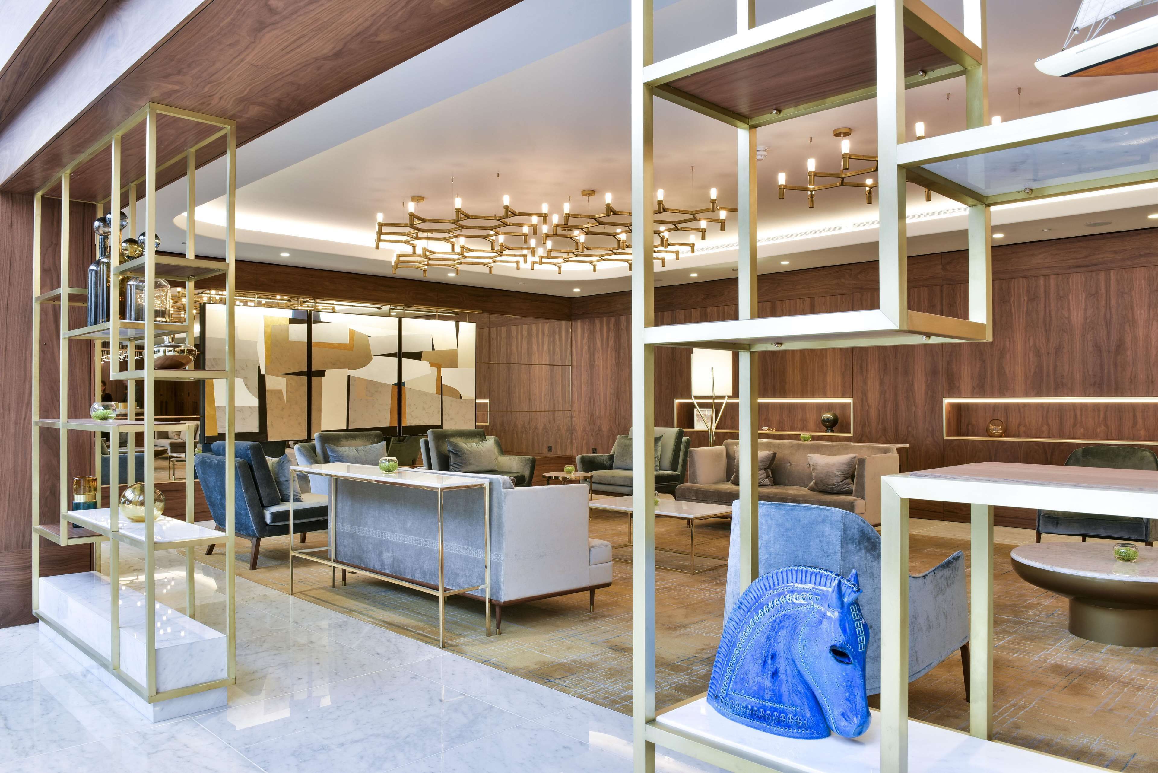A modern interior with a central seating area, a chandelier, and a decorative blue item on a table.